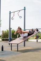 Happy woman working out on the sports ground in sunny summer day, training her back photo