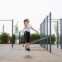 Mujer feliz trabajando en el campo de deportes en un día soleado de verano saltar la cuerda foto