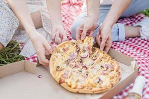 Young couple having picnic eating pizza photo