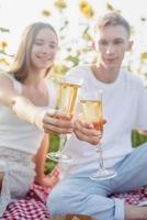 Young couple having picnic on sunflower field at sunset photo