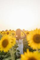 young beautiful woman between sunflowers in sunset photo