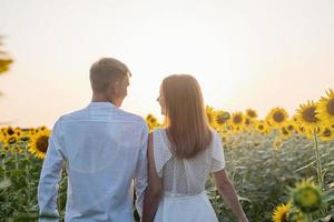 Beautiful couple walking together in sunflowers fields in sunset photo