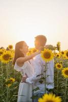 hermosa pareja divirtiéndose en campos de girasoles foto