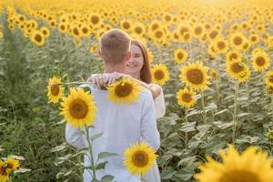 hermosa pareja divirtiéndose en campos de girasoles foto