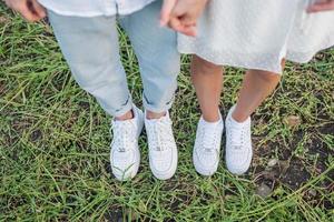pareja de pie en el campo de hierba. pies y zapatos de pareja joven.