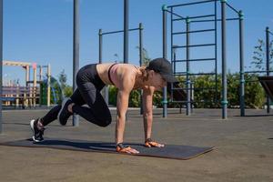 Sportive woman working out on the sports ground in sunny summer day photo