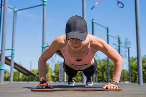 Sportive woman working out on the sports ground in sunny summer day photo