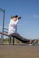 Joven deportista en guantes deportivos de agua potable en el campo de deportes foto