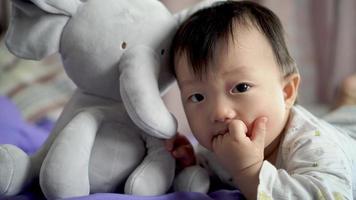 Close up cute baby chew finger and then smile beside plush toy video