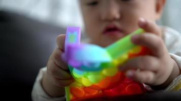 Nahaufnahme der Hand des kleinen Jungen kauen Regenbogenfarben-Sinnesspielzeug video