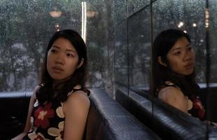 Joven y bella mujer asiática con cara triste y linly sentado en la cafetería en un día lluvioso con el reflejo del espejo foto