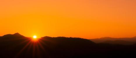 hermoso paisaje de montaña y amanecer con cielo naranja foto