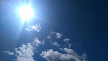 Sun, sky and clouds. Sun on the background of a blue sky with white clouds photo