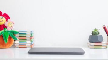 Closed laptop on the desktop with colored books. Children's workplace, learning online in quarantine photo