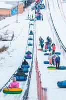 gente montando tubos de nieve en el parque de invierno foto