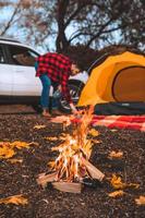 Bonfire in front of camping site tent with car and person on background photo