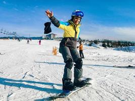 Woman riding on snowboard down by hill photo