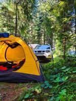 Carpa amarilla con coche todoterreno en el bosque foto