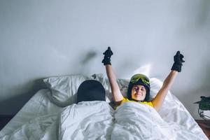 Woman sleeping in bed with snowboard dreaming about ski at snow mountains photo