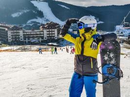 Woman standing at ski resort hill with snowboard photo