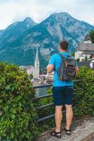 Hombre con mochila mirando a la ciudad de Hallstatt foto