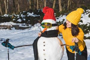 mujer sonriente, cerca, esquiador, muñeco de nieve foto