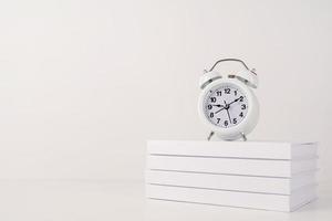 White alarm clock on stack of books, mockup design photo