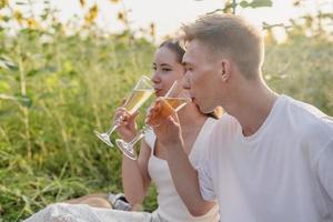 Pareja joven haciendo un picnic en el campo de girasol al atardecer foto