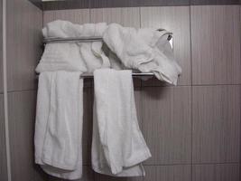 White towels hang on a hanger in the bathroom photo