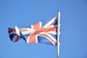 The flag of Great Britain flies in the wind against a blue sky photo