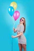 Happy smiling woman is looking on an air colorful balloons having fun over a blue background photo