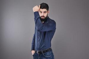 Handsome young bearded man is looking away while standing against gray background photo