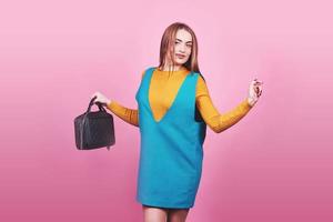 Beautiful woman wearing nice clothes, handbag posing on pink background. Fashion spring photo