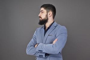 Portrait of freelancer man with beard in jacket standing against gray backdrop photo