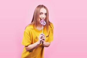 Girl cute funny portrait holding lollipop smiling on pink background. Beautiful multicultural Caucasian girl smiling happy photo