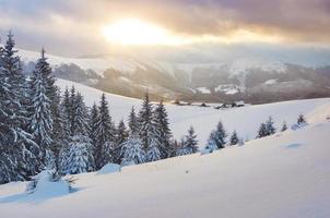 majestuosa puesta de sol en un pequeño pueblo en una colina nevada bajo ucraniano. pueblos en las montañas en invierno. hermoso paisaje de invierno. Cárpatos, Ucrania, Europa