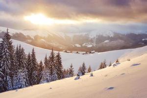 Majestic sunset at small village on a snowy hill under Ukrainian. Villages in the mountains in winter. Beautiful winter landscape. Carpathians, Ukraine, Europe photo