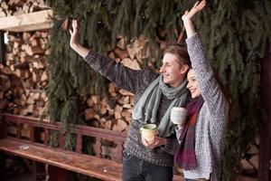Photo of happy man and pretty woman with cups outdoor in winter. Winter holiday and vacation. Christmas couple of happy man and woman drink hot coffe. Hello neighbors