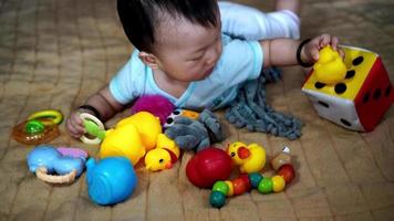 bebé chino acostado en la cama y masticar un juguete video