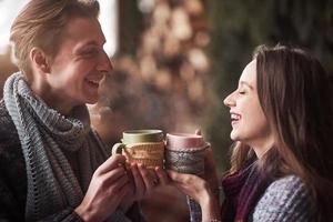 Young couple having breakfast in a romantic cabin outdoors in winter. Winter holiday and vacation. Christmas couple of happy man and woman drink hot wine. Couple in love photo