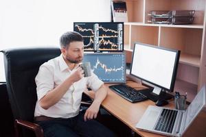 Stockbroker in shirt is working in a monitoring room with display screens. Stock Exchange Trading Forex Finance Graphic Concept. Businessmen trading stocks online photo