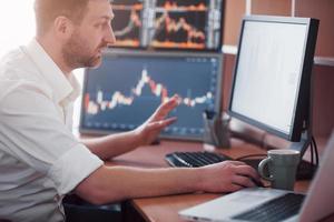 Stockbroker in shirt is working in a monitoring room with display screens. Stock Exchange Trading Forex Finance Graphic Concept. Businessmen trading stocks online photo