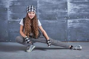 Young beautiful girl dancing in a trendy clothes on a grunge background photo