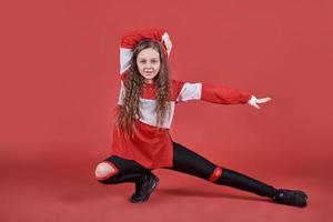 Young urban woman dancing on red background, modern slim hip-hop style teenage girl photo
