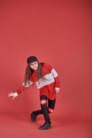 Young beautiful cute girl dancing on red background, modern slim hip-hop style teenage girl jumping