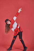 Joven hermosa linda chica bailando sobre fondo rojo, moderno y delgado estilo hip-hop adolescente saltando