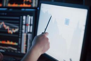 Analyzing data. Close-up of young businessman pointing on the data presented in the chart with pen while working in creative office photo