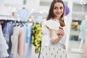 mujer de compras. mujer feliz con bolsas de la compra y tarjeta de crédito disfrutando de compras. consumismo, compras, concepto de estilo de vida foto