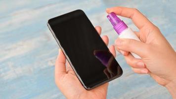 Close-up shot of Spray and wipe the alcohol to clean and kill germs on the smartphone.