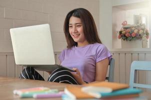 las mujeres jóvenes usan la computadora portátil para chatear por video en línea con un amigo. ella sonríe feliz. foto